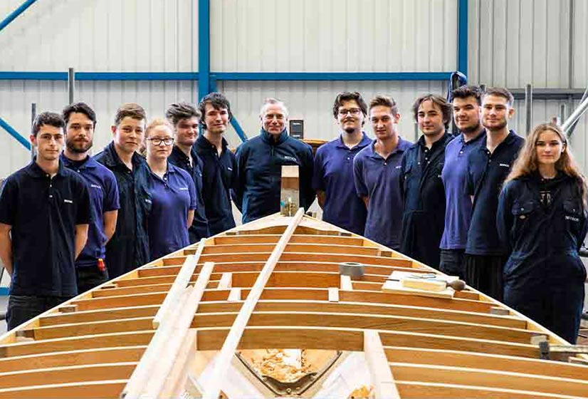 Berthon's new 2019-20 apprentices behind a boat being restored